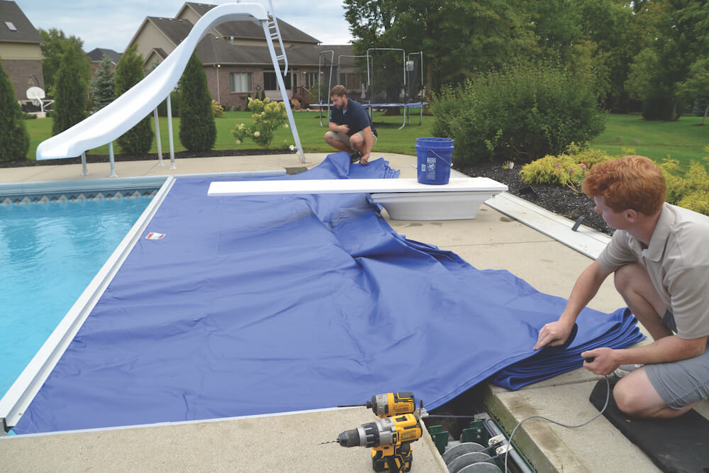 technicians replacing automatic pool cover