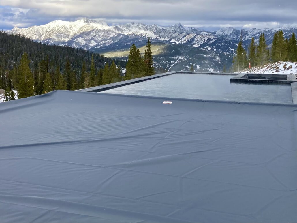 negative edge pool with cover partially closed and mountains in distance