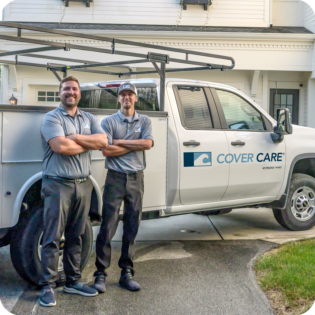 two Cover Care technicians standing near their service truck with their arms crossed
